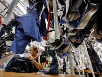 Maria Agomes, stitches suit jackets under a conveyor system that carries the garments from one station to the next, at the Joseph Abboud manufacturing plant in New Bedford, MA.   [ PETER PEREIRA/THE STANDARD-TIMES/SCMG ]